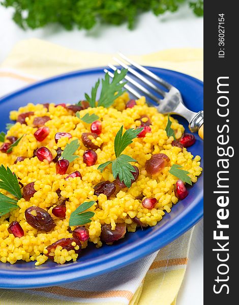 Couscous with curry, dried cranberries and herbs on the plate, vertical