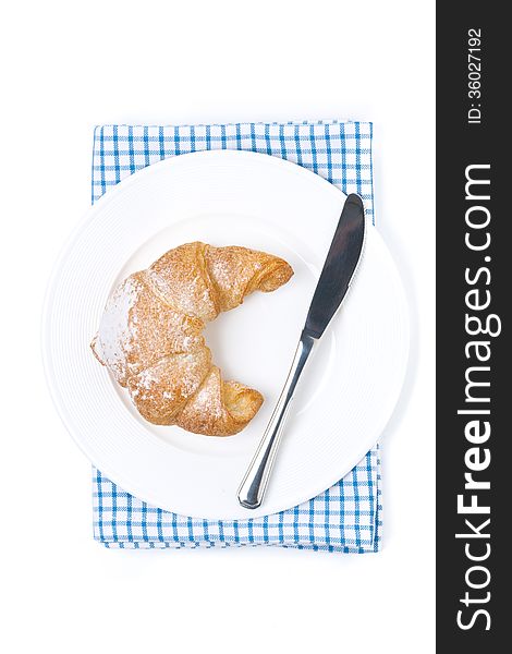 Croissant and a knife on a plate isolated