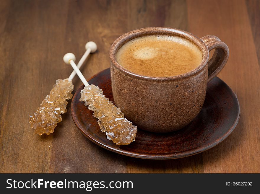 Cup of coffee and caramel sugar on sticks, close-up