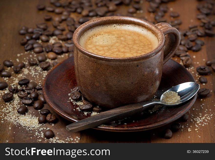 Espersso cup, sugar and coffee beans on wooden table, selective focus, close-up