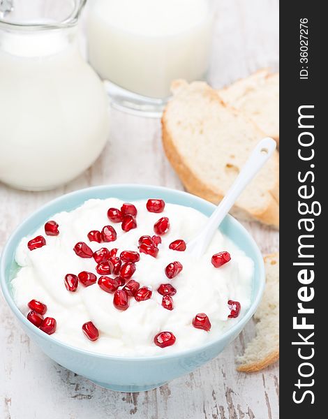 Homemade yogurt with pomegranate, milk and bread for breakfast, vertical