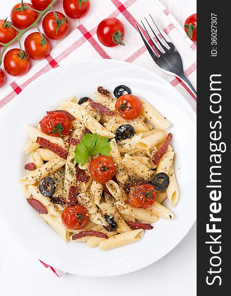 Pasta with sausage, tomatoes and olives, top view, vertical