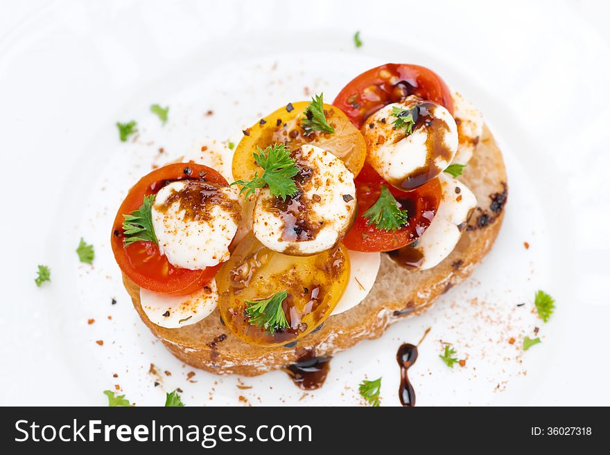 Piece of ciabatta with mozzarella, balsamic sauce and colorful cherry tomatoes, top view, close-up. Piece of ciabatta with mozzarella, balsamic sauce and colorful cherry tomatoes, top view, close-up