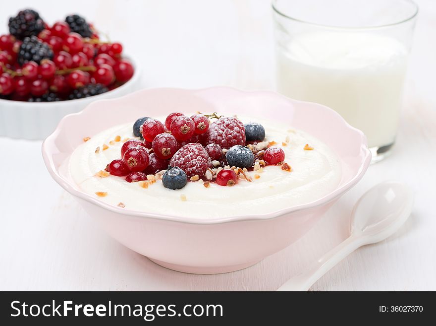 Semolina porridge with fresh berries, nuts and glass of milk, close-up, horizontal