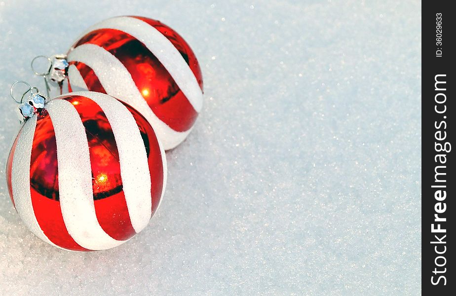 Red and white striped Christmas ornaments on fresh snow background with copy space, ideal for greeting card or party invitation. Red and white striped Christmas ornaments on fresh snow background with copy space, ideal for greeting card or party invitation.