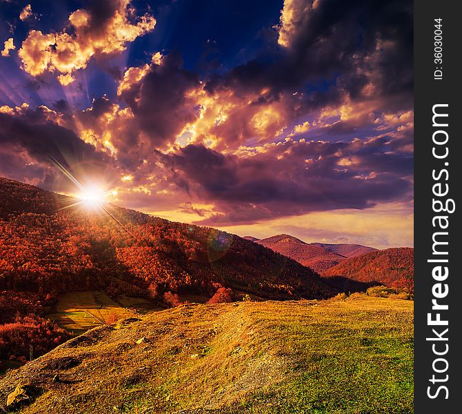 Autumn landscape. forest on a hillside covered with red and yellow leaves. over the mountains against blue sky clouds in evening. Autumn landscape. forest on a hillside covered with red and yellow leaves. over the mountains against blue sky clouds in evening