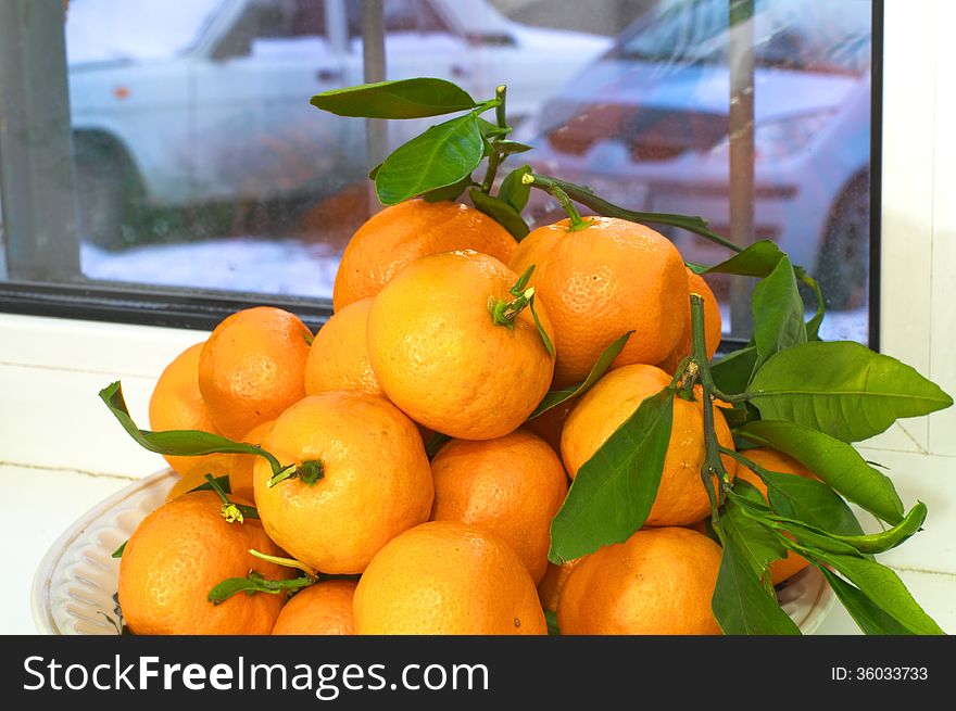 Mandarines with leaves. Winter behind the window.