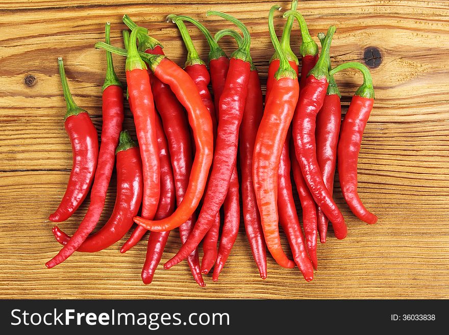 Red, fresh cayenne peppers on a wooden background.