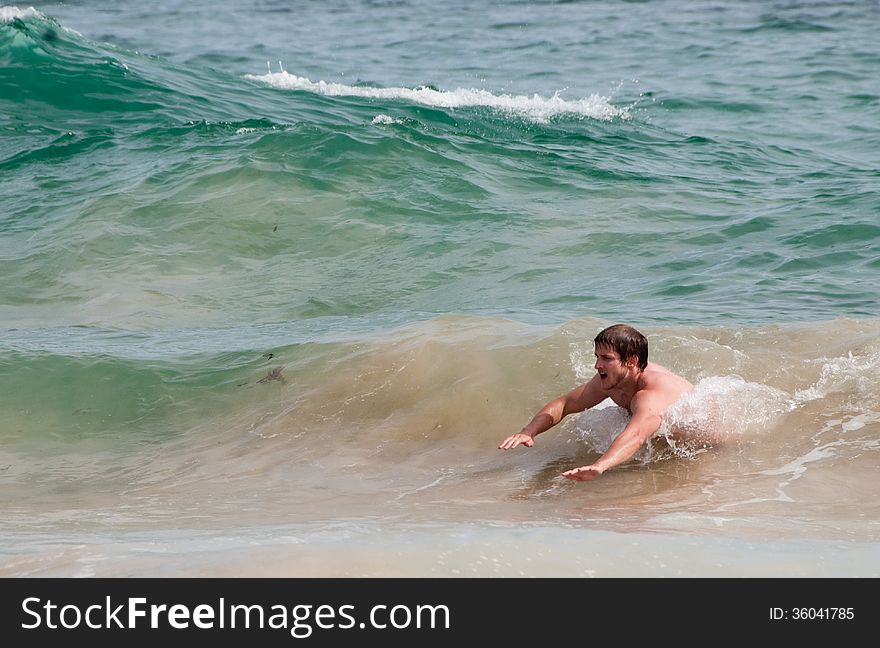 A young man body surfs through waves on a beach in South Africa. A young man body surfs through waves on a beach in South Africa.