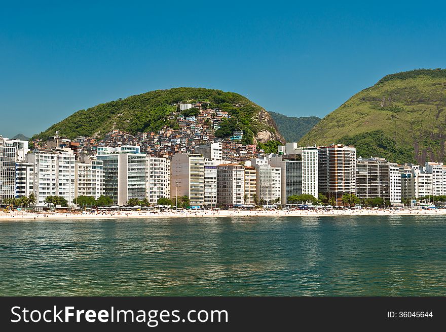 Luxury residential apartment and hotel buildings in the front of the Copacabana beach with mountains behind in Rio de Janeiro, Brazil. Luxury residential apartment and hotel buildings in the front of the Copacabana beach with mountains behind in Rio de Janeiro, Brazil.