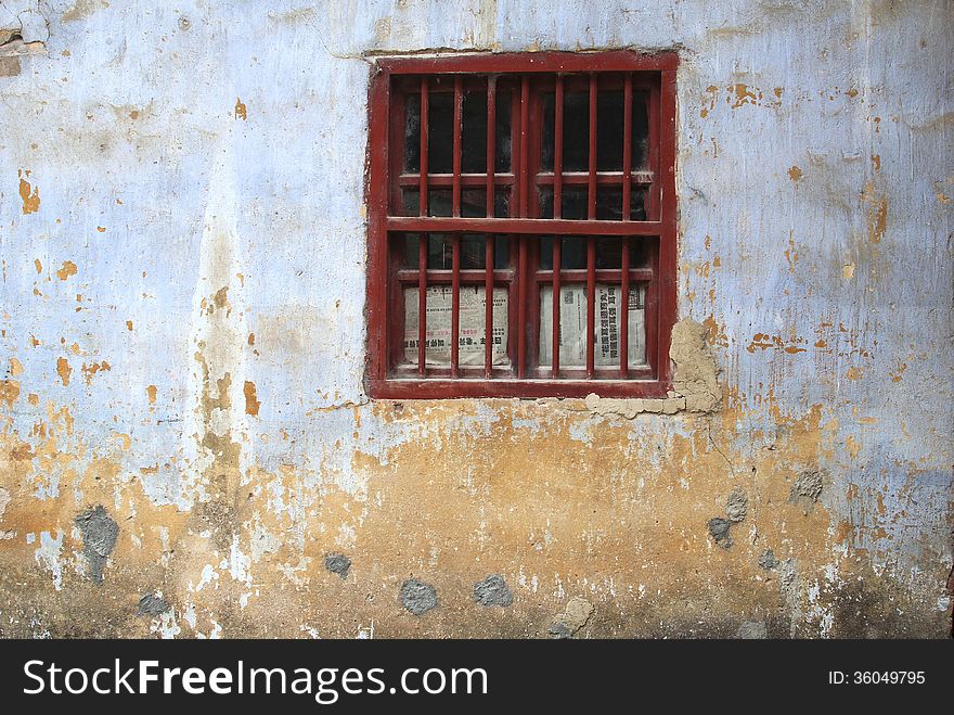 Window with bars and newspapers in an old grungy wall, Daxu, China