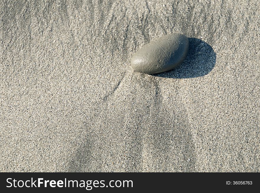 Pebble on beach sand with surf traces