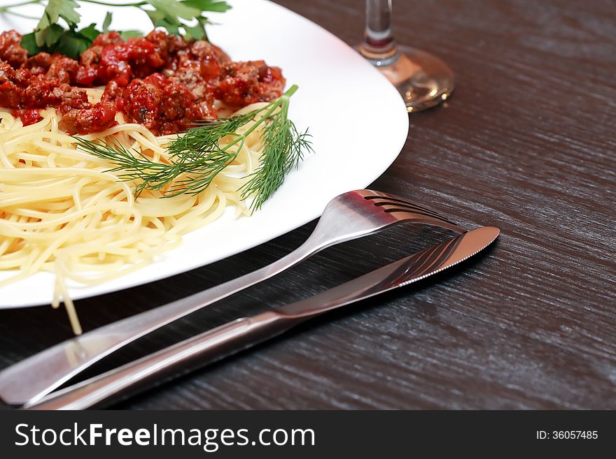 Closeup of plate with pasta near fork and knife on wooden table. Closeup of plate with pasta near fork and knife on wooden table