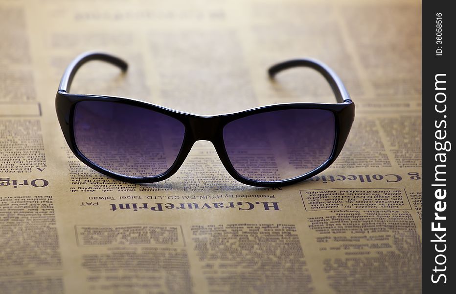 A pair of sunglasses on newspaper background.