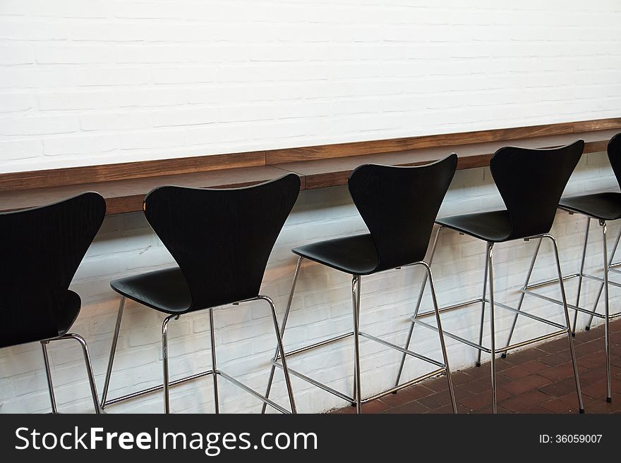 Modern designer minimalistic style chairs in line opposite a white wall. Modern designer minimalistic style chairs in line opposite a white wall