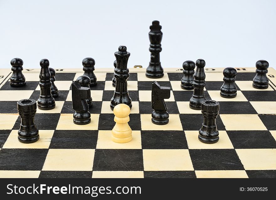 White pawn standing alone, surrounded by black chess figures