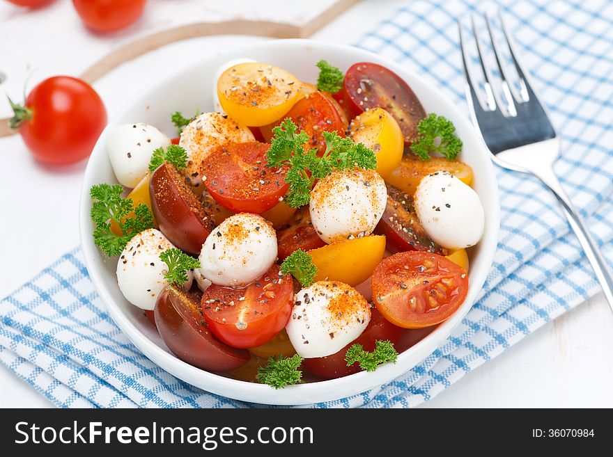 Salad with mozzarella, fresh herbs and colorful cherry tomatoes, close-up, horizontal