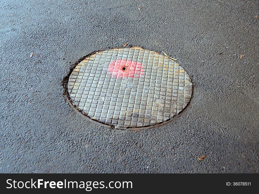 Round cover of a manhole against asphalt. Round cover of a manhole against asphalt
