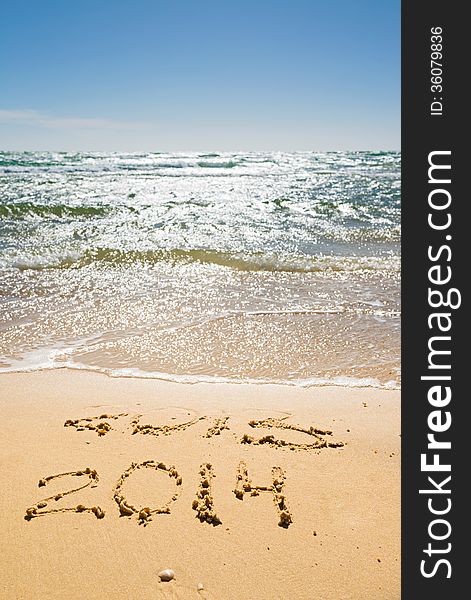 Digits 2013 and 2014 on the sand seashore - concept of new year and passing of time. Digits 2013 and 2014 on the sand seashore - concept of new year and passing of time