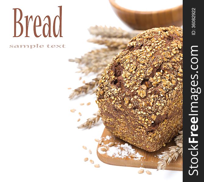 Whole grain bread with seeds and a bowl of flour, isolated