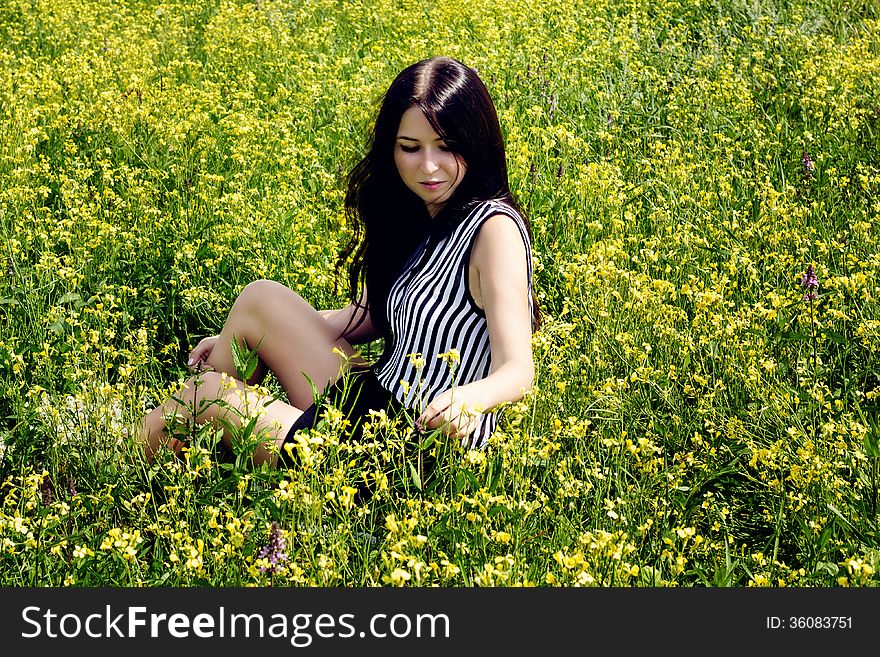 Happy woman sitting on yellow sunny flowers field