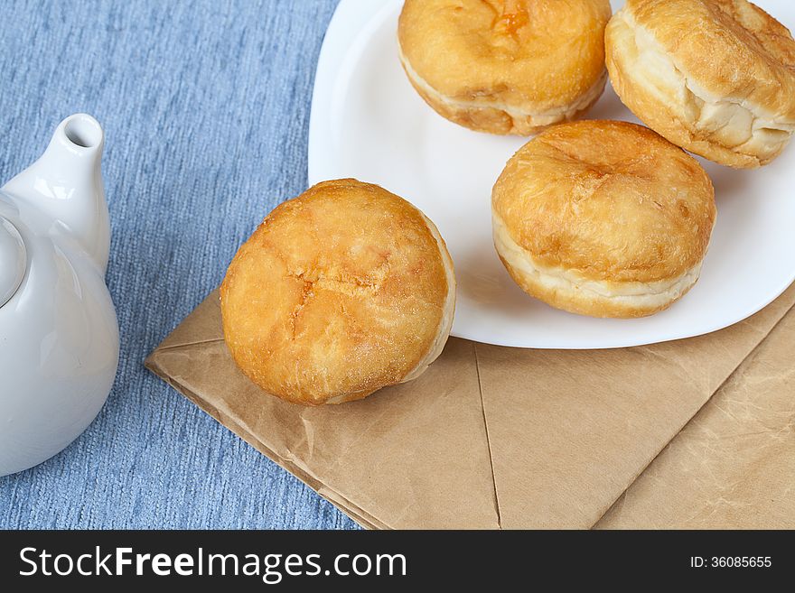 Jelly filled Bismark doughnuts on white plate over craft packet, ready to eat. Jelly filled Bismark doughnuts on white plate over craft packet, ready to eat