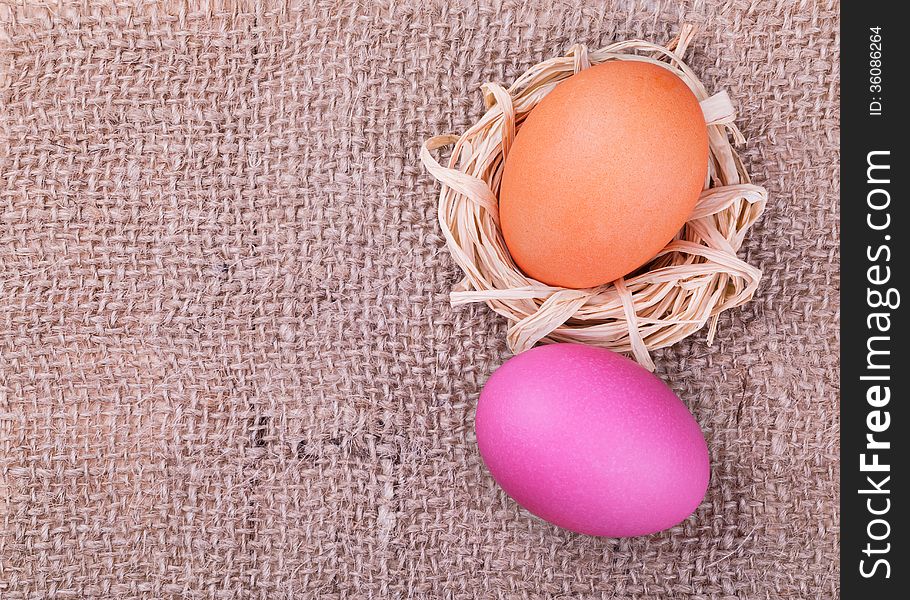 Easter eggs on burlap background, top view