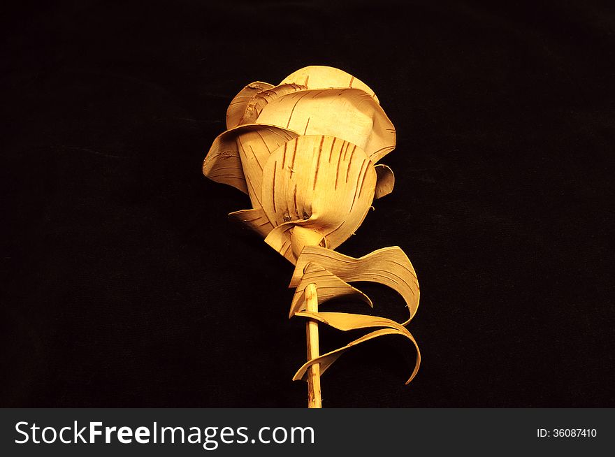 Rose flower made of birch bark on black velvet