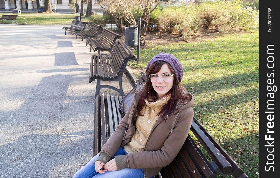 Beautiful young girl sitting on a bench outdoor in a park. Beautiful young girl sitting on a bench outdoor in a park.