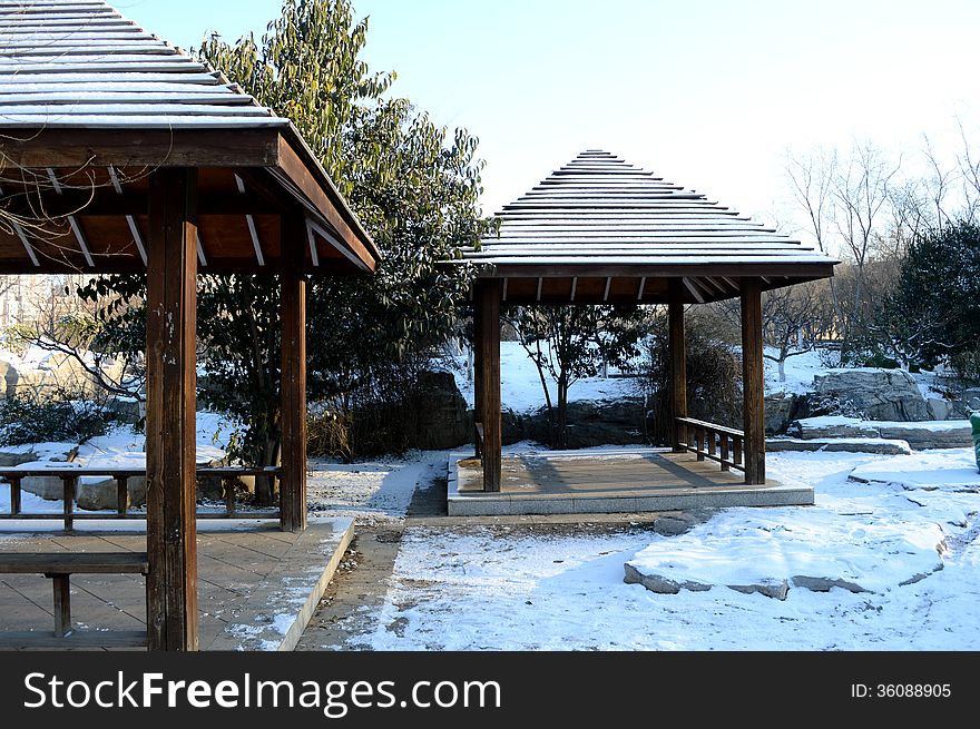 two white pavilions in a park after snow