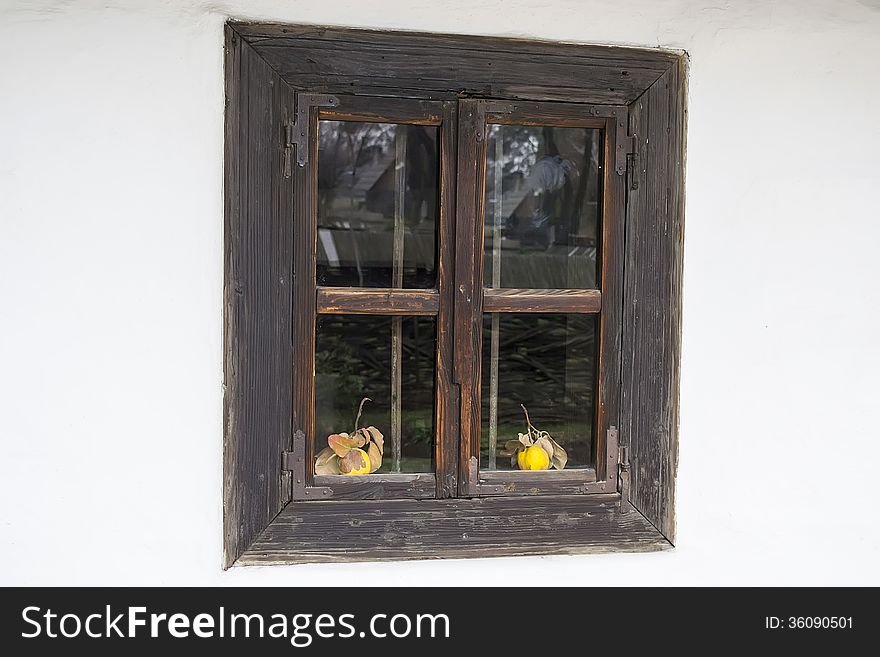 An old window with two quinces in front on a white wall background.