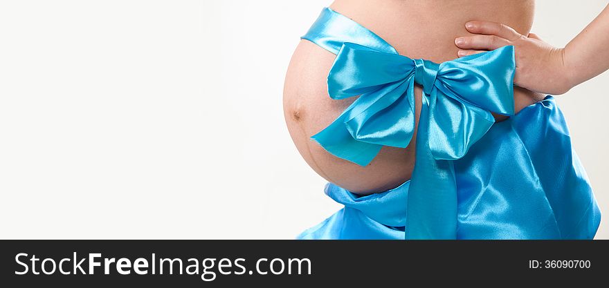 On the abdomen of a pregnant woman tied blue bow. On the abdomen of a pregnant woman tied blue bow