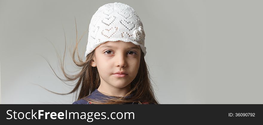 Portrait of a girl in a white knitted cap with flying hair. Portrait of a girl in a white knitted cap with flying hair