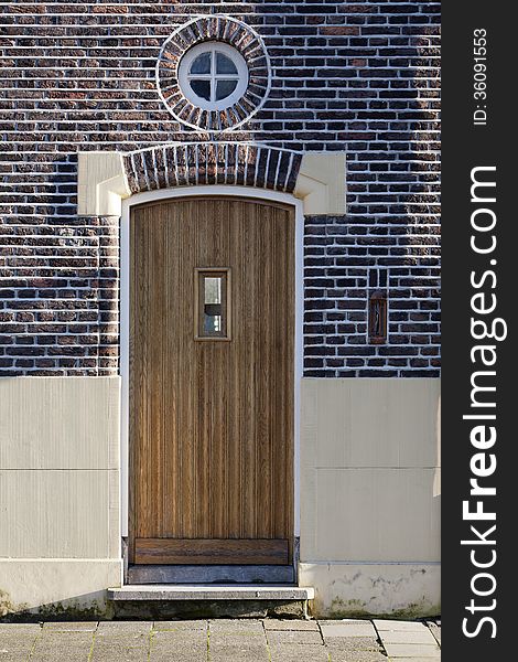 Wooden door and round window in Vlaardingen, the Netherlands. It looks like a person who welcomes you with open arms.