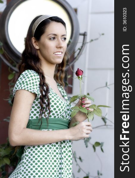 Attractive young woman in green dress holding a single  red rose. Attractive young woman in green dress holding a single  red rose