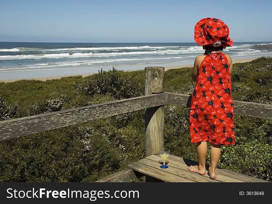 Girl in red dress looking out to the sea. Girl in red dress looking out to the sea