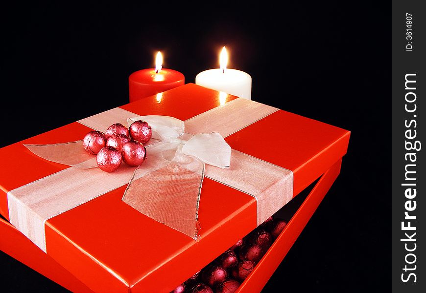 A gift package and candles against a black background. A gift package and candles against a black background.