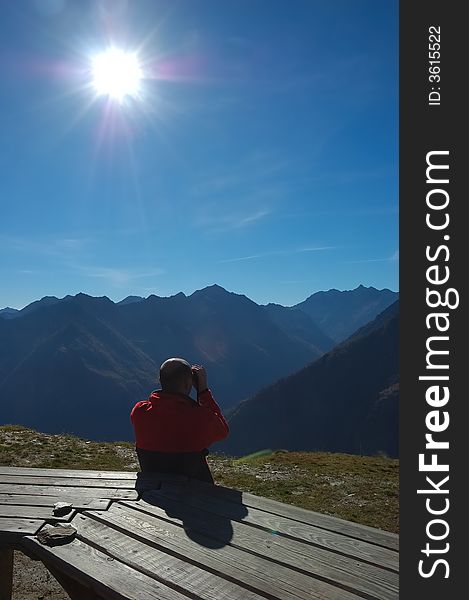 Man looking at alpine panorama with binoculars. Man looking at alpine panorama with binoculars