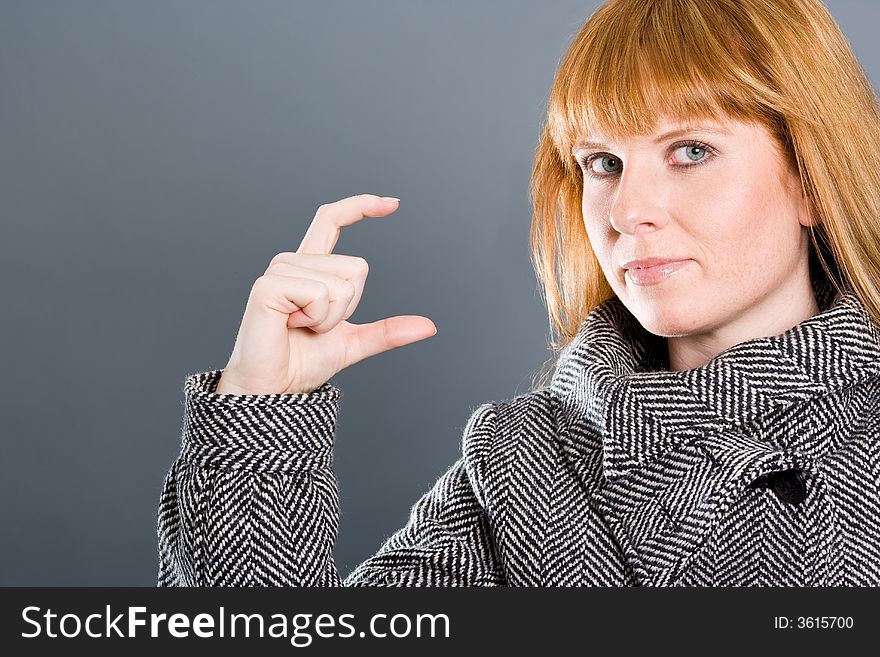 Woman with coat showing a small gap or small thing with her fingers. Woman with coat showing a small gap or small thing with her fingers.