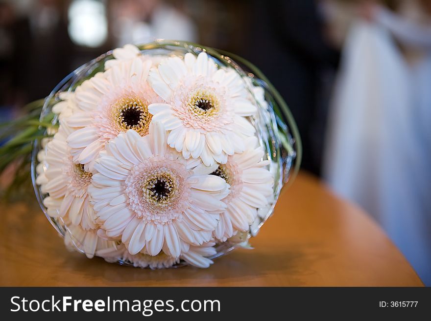 A Bouquet of flowers on a desk. It's a bridal bouquet.