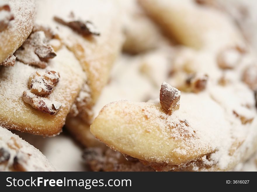 A detail of a pile of baked rolls with wallnuts and powdered sugar.