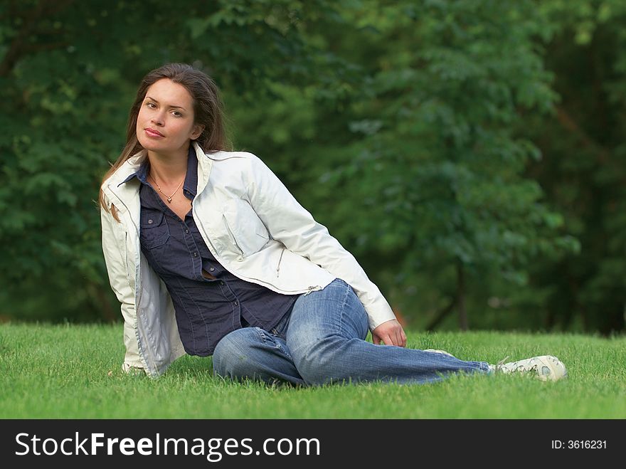 Pretty brunette relaxing on a fresh grass in a park. Pretty brunette relaxing on a fresh grass in a park