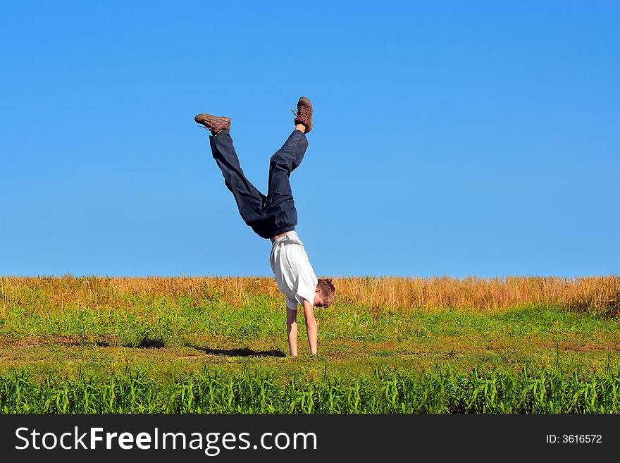 Somersault on grass on the blue sky background. Somersault on grass on the blue sky background