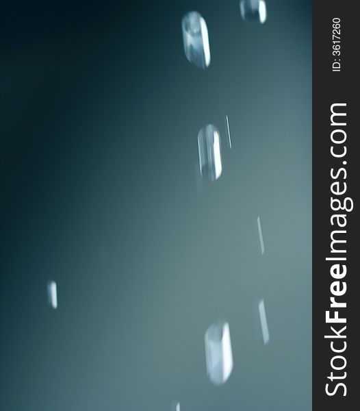 Falling water drops from eaves - abstract blue background