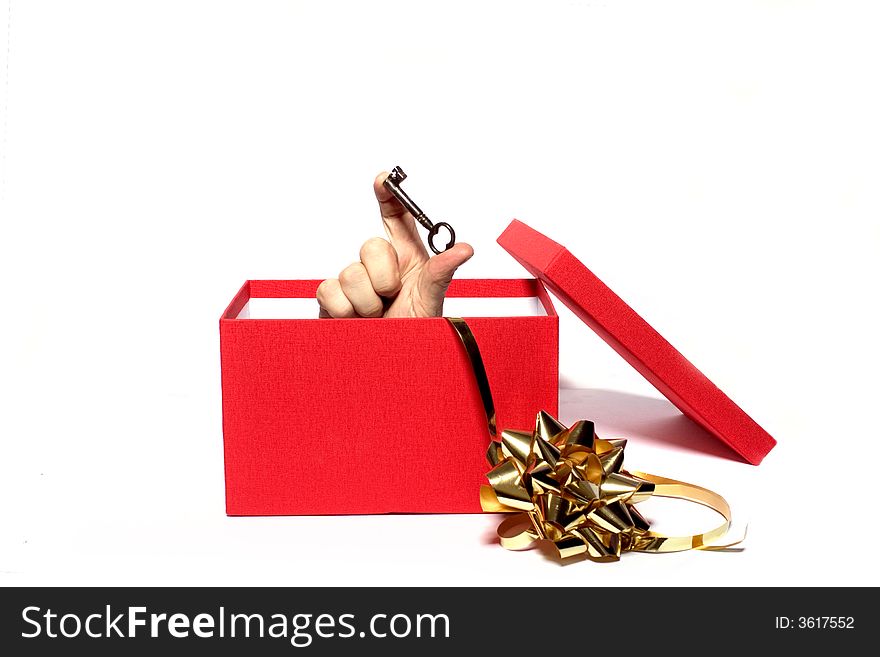 A key being held from inside a gift box. A key being held from inside a gift box