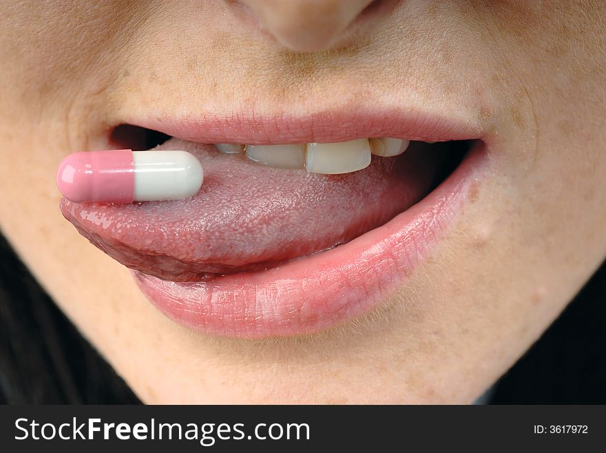 Young woman's face with pink pill. Young woman's face with pink pill