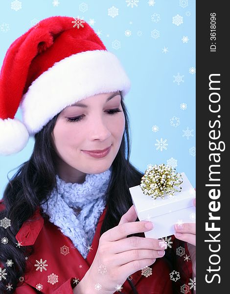 A young woman looking at a Christmas gift, surrounded by snowflakes