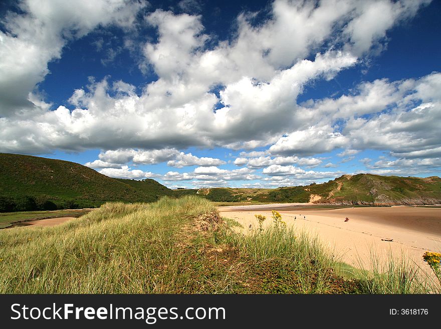 Wide angle shot of dunes, blue sky and white fluffy cumulus. Wide angle shot of dunes, blue sky and white fluffy cumulus