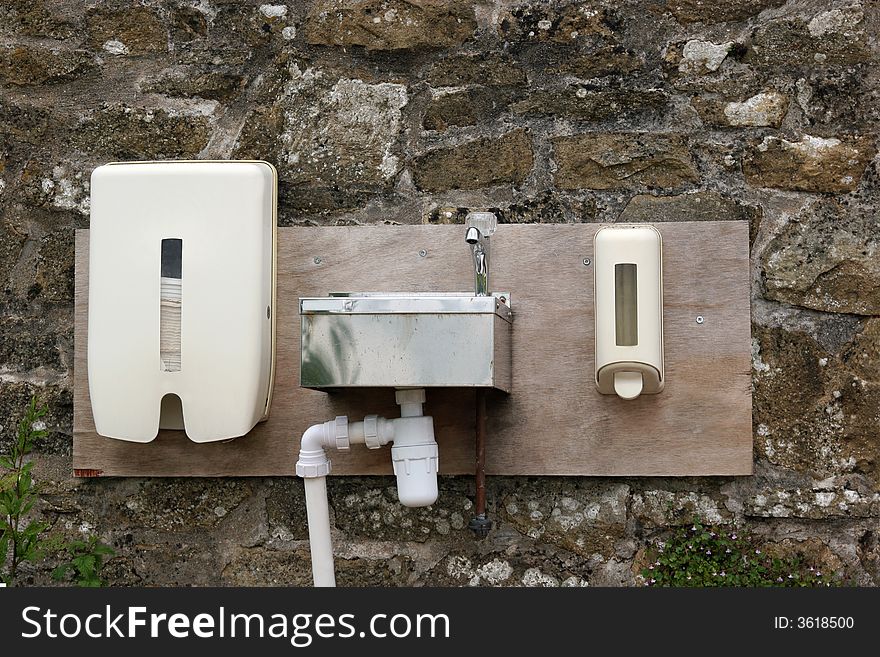 Outdoor metal wash basin, plastic hand towel and soap dispenser fixed to an old stone wall. Outdoor metal wash basin, plastic hand towel and soap dispenser fixed to an old stone wall.