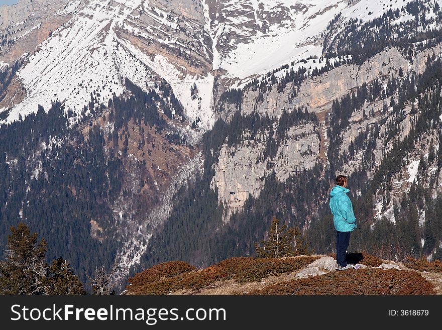 Lone woman standing on top of a deep valley in the french alps. Lone woman standing on top of a deep valley in the french alps